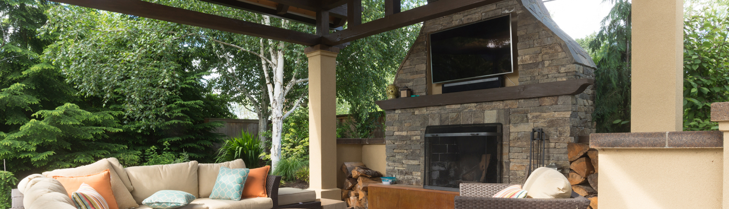 patio furniture on paved back patio with tv and large stone fireplace