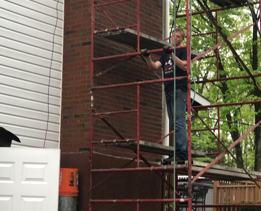 construction worker on scaffolding next to masonry chimney