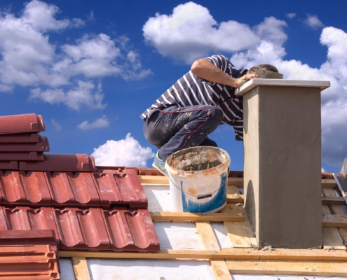 Image of a worker repairing a chimney with sealant.