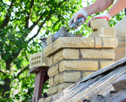 Repairing a brick chimney with bricklaying. Building contractor is rebuidling a chimney on a house