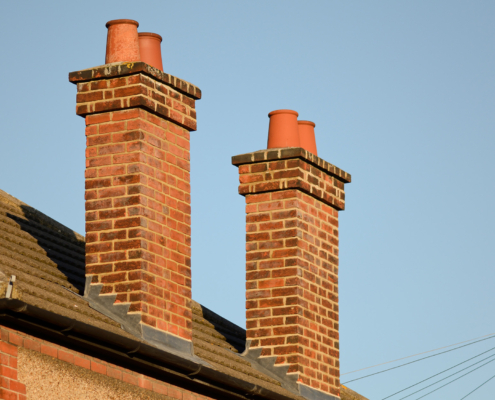 Side view of two brick chimneys on a home side by side
