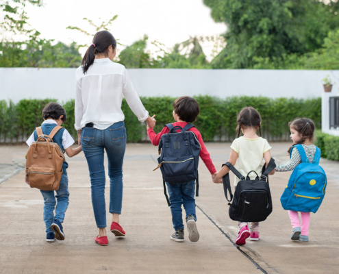 Group of preschool student and teacher holding hands and walking to home