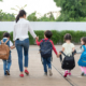Group of preschool student and teacher holding hands and walking to home