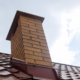 Worms eye view of an orange brick chimney on a red clay tile roof