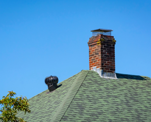 Brick chimney and metal vent on a house shingled roof in Boston, USA
