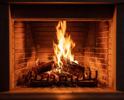 Fireplace burning firewood, fire flames on wood logs, bricks background