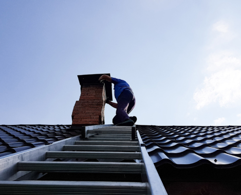a chimney sweep climbs a metal ladder to the roof of the bathhouse to clean the pipe from burning