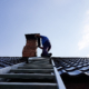 a chimney sweep climbs a metal ladder to the roof of the bathhouse to clean the pipe from burning